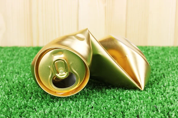 Crumpled empty can on grass on wooden background — Stock Photo, Image