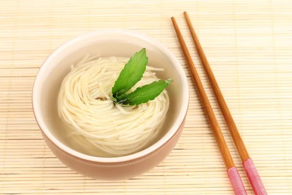 Tagliatelle asiatiche in ciotola su tappetino di bambù — Foto Stock