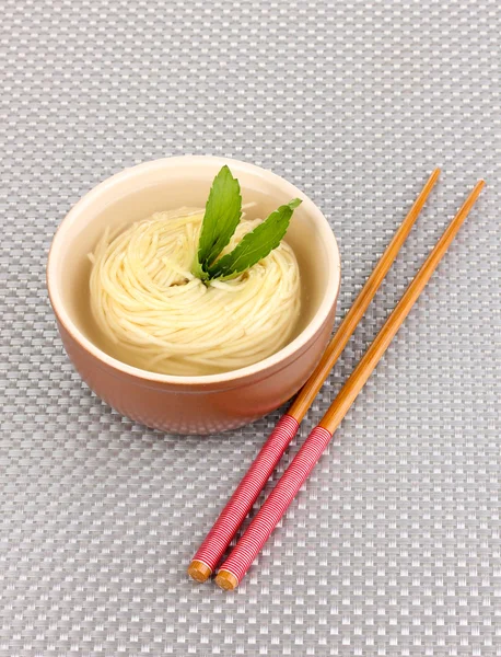 Asian noodles in bowl on grey mat — Stock Photo, Image