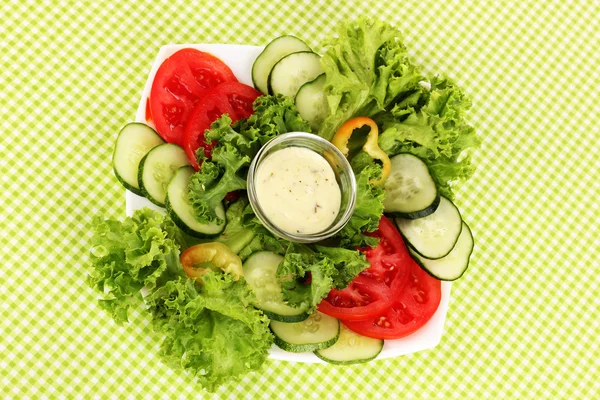 Chopped vegetables and sauce on plate on green tablecloth — Stock Photo, Image