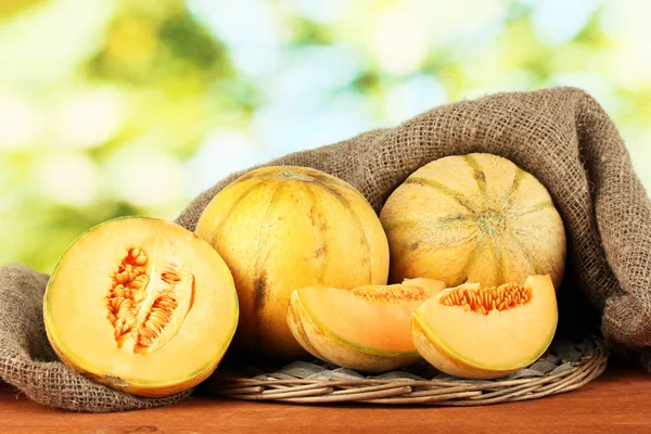 Cut melon on wicker mat on green background close-up — Stock Photo, Image