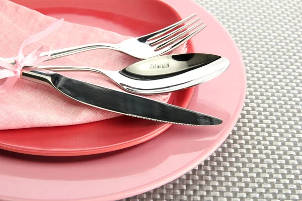 Pembe boş tabak çatal, kaşık ve bıçak üzerinde gri bir masa örtüsü — Stok fotoğraf