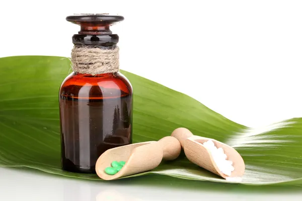 Medicine bottle with tablets on green leaf isolated on white — Stock Photo, Image