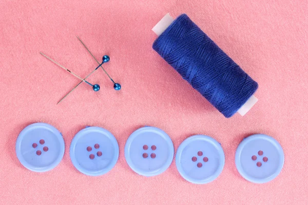 Bottoni da cucito colorati con filo su tessuto rosa — Foto Stock