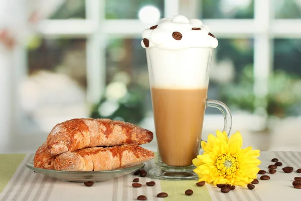 Стакан свежего кофе и блюдце с бубликами на столе — стоковое фото