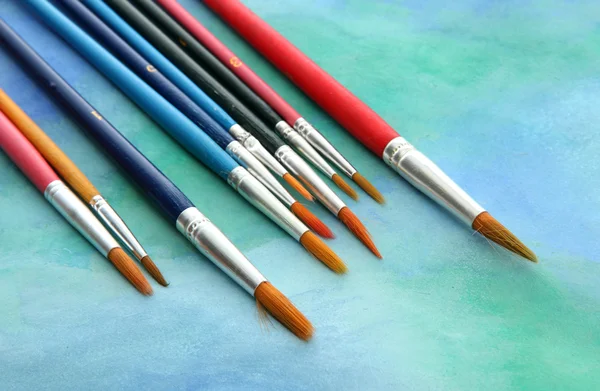 Brushes on bright abstract gouache painted background — Stock Photo, Image