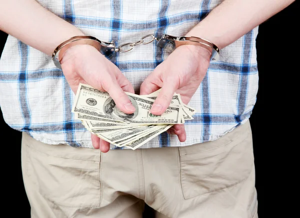 Man in handcuffs is holding dollars, on black background — Stock Photo, Image