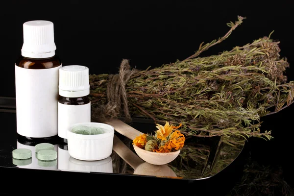 Frascos de medicamentos y hierbas sobre fondo negro. concepto de homeopatía —  Fotos de Stock