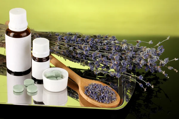 Garrafas de medicamentos e ervas no fundo verde. conceito de homeopatia — Fotografia de Stock
