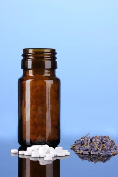 Frasco con pastillas y hierbas sobre fondo azul. concepto de homeopatía — Foto de Stock