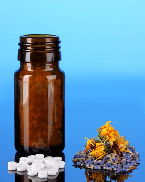 Flasche mit Pillen und Kräutern auf blauem Hintergrund. Konzept der Homöopathie — Stockfoto