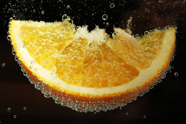 Rebanada de naranja en el agua con burbujas, sobre fondo negro —  Fotos de Stock