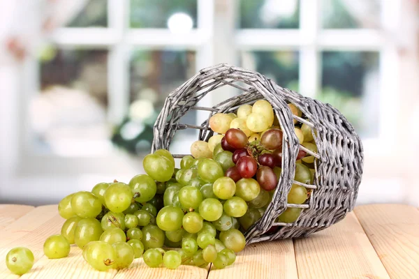 Uvas verdes maduras em cesta na mesa de madeira no fundo da janela — Fotografia de Stock