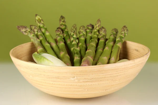 Frischer Spargel in Holzschale auf buntem Hintergrund — Stockfoto