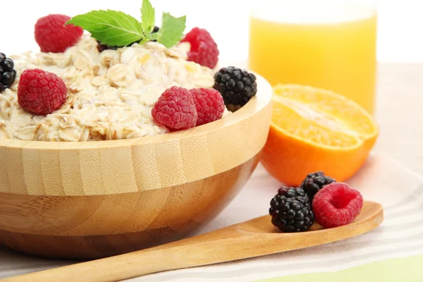 Tasty oatmeal with berries and glass of juice, on wooden table — Stock Photo, Image