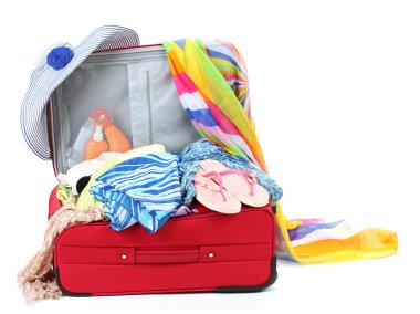 Suitcase with summer clothes, a hat and suntan isolated on white