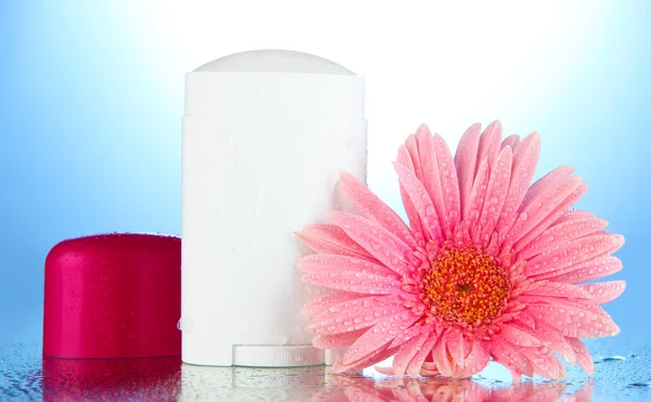 Deodorant with flower on blue background — Stock Photo, Image