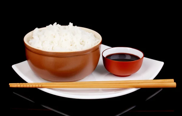 Cuenco de arroz y palillos en plato sobre fondo gris — Foto de Stock