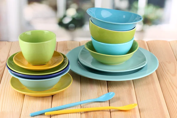 Colorful tableware on wooden table on window background — Stock Photo, Image