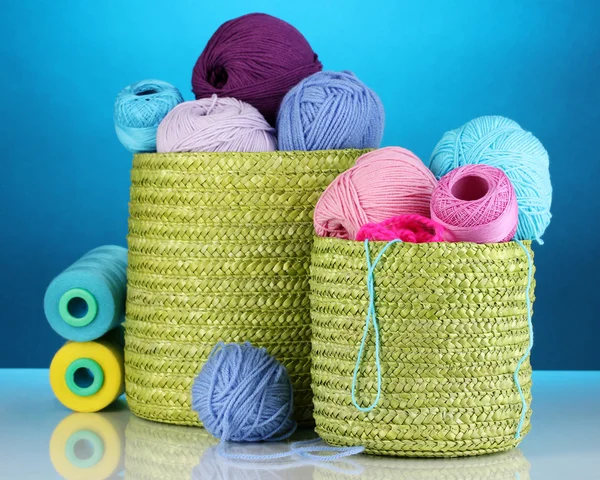 Colorful yarn for knitting in green basket on blue background — Stock Photo, Image