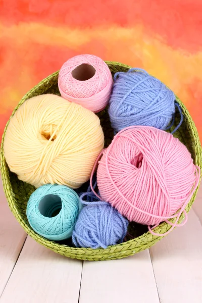 Colorful yarn for knitting in green basket on white wooden table on colorfu — Stock Photo, Image