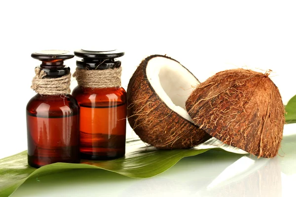 Kokosolja i flaskor med kokosnötter på vit bakgrund — Stockfoto