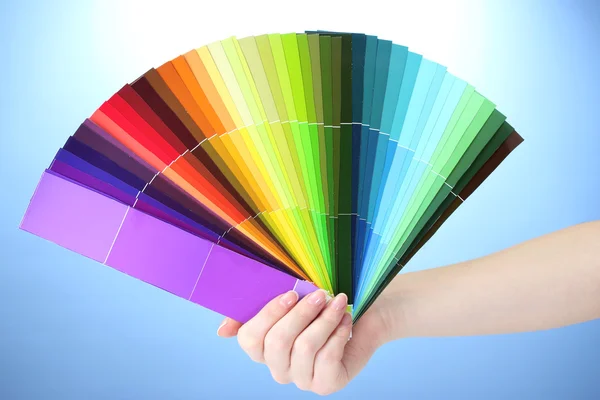 Hand met helder palet van kleuren op blauwe achtergrond — Stockfoto