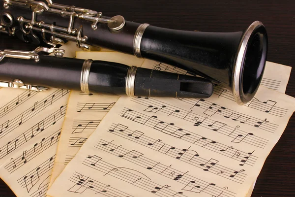 Musical notes and clarinet on wooden table — Stock Photo, Image