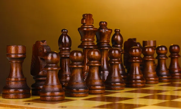 Schackbräde med schackpjäser på brun bakgrund — Stockfoto