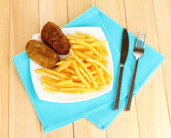 Batatas fritas com hambúrgueres no prato em fundo de madeira close-up — Fotografia de Stock