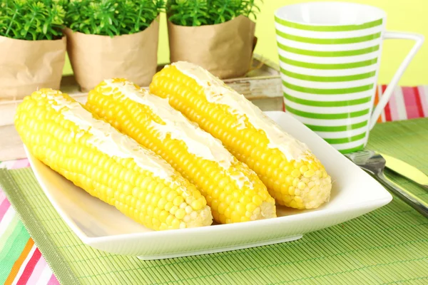 Boiled corn with butter on a green background — Stock Photo, Image