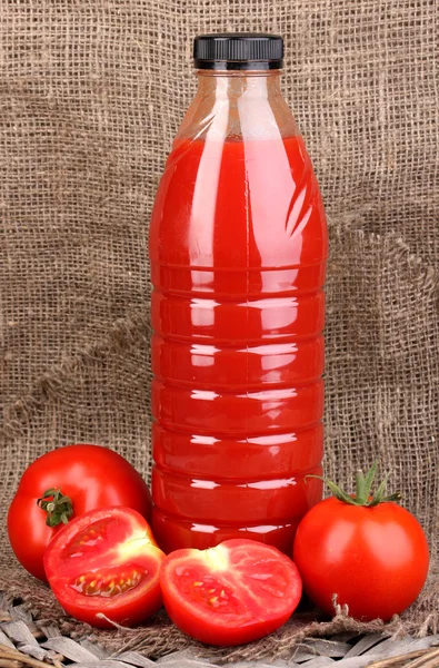 Succo di pomodoro in bottiglia su fondo sacco — Foto Stock