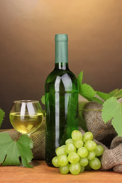 Garrafa de grande vinho com vidro sobre mesa de madeira sobre fundo marrom — Fotografia de Stock