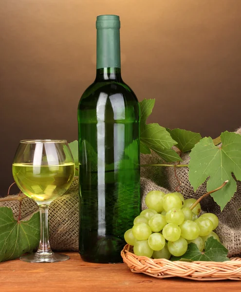 茶色の背景に木製のテーブルの上のガラスと偉大なワインのボトル — ストック写真