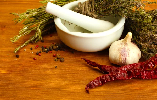 dried herbs in mortar and vegetables, on wooden background