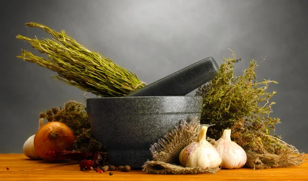 Hierbas secas en mortero y verduras, sobre mesa de madera sobre fondo gris —  Fotos de Stock