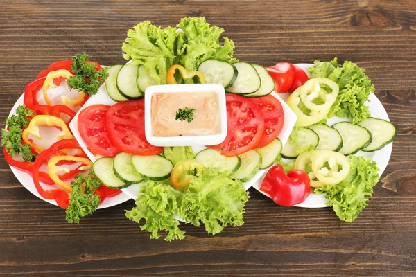 Verduras picadas y salsa en plato sobre mesa de madera — Foto de Stock