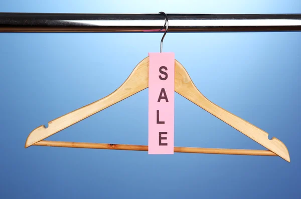 Wooden clothes hanger as sale symbol on blue background — Stock Photo, Image
