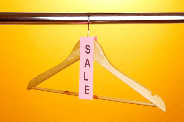 Wooden clothes hanger as sale symbol on orange background — Stock Photo, Image