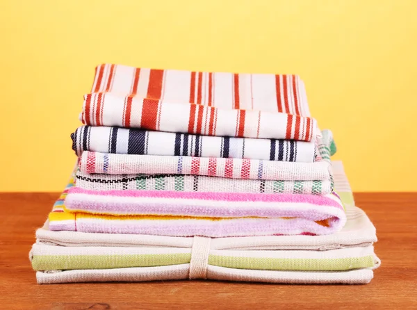 Kitchen towels on wooden table on orange background close-up — Stock Photo, Image