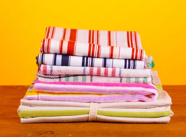 Kitchen towels on wooden table on orange background close-up — Stock Photo, Image