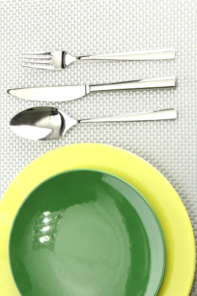 Green empty plates with fork, spoon and knife on a grey tablecloth — Stock Photo, Image