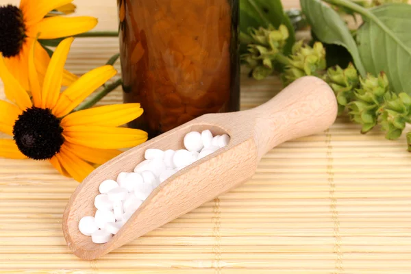 Medicine bottle with tablets and flowers on bamboo mat — Stock Photo, Image