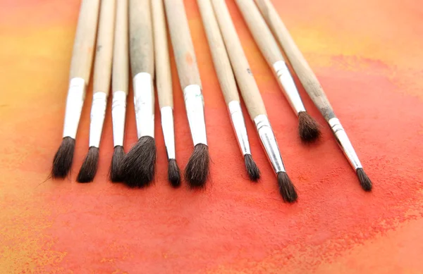 Brushes on bright abstract gouache painted background — Stock Photo, Image