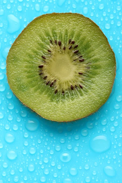 Tranche de kiwi avec goutte sur fond bleu — Photo
