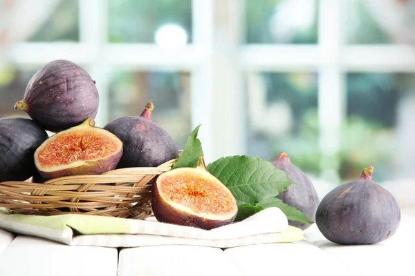 Ripe sweet figs with leaves in basket, on wooden table, on window backgroun — Stock Photo, Image