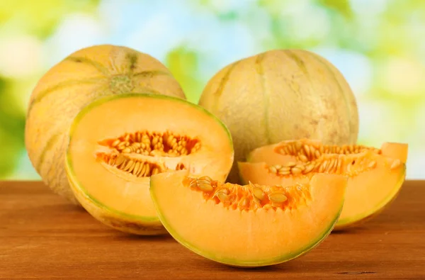 Cut melon on wooden table on green background — Stock Photo, Image