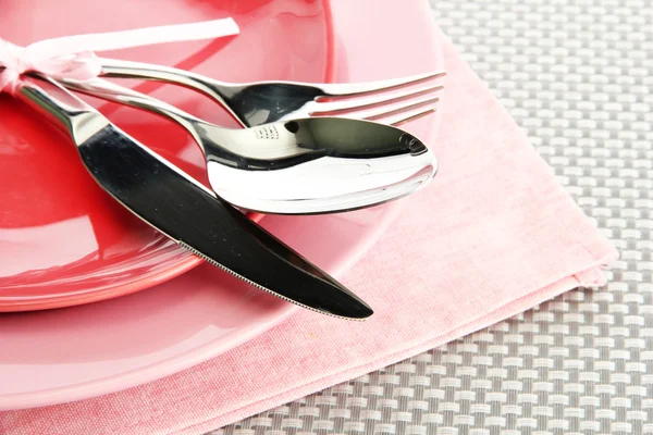 Pink empty plates with fork, spoon and knife on a grey tablecloth — Stock Photo, Image