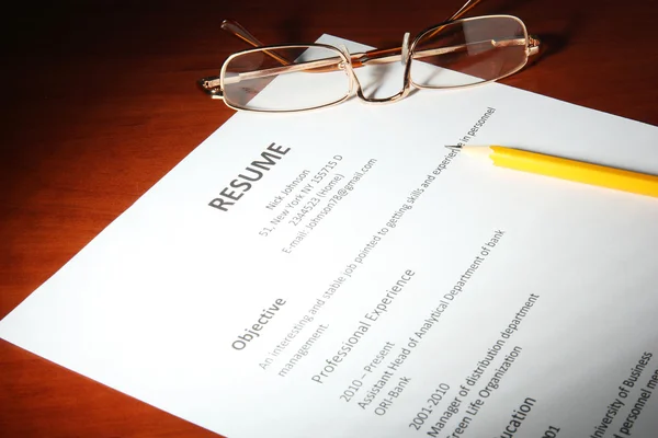 Closeup of resume with glasses and pencil on wooden table — Stock Photo, Image