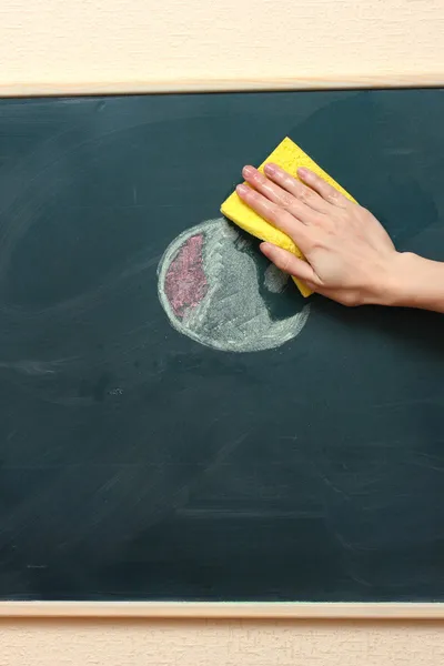 Mano con una esponja amarilla limpiando la pizarra — Foto de Stock